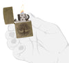 Briquet Zippo laiton antique gravure arbre de vie, ouvert avec flamme dans une main stylisée
