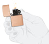 Briquet Zippo modèle de base en cuivre massif brossé et insert noir ouvert avec flamme dans une main stylisée