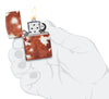 Briquet Zippo 540° vue de face en main stylisée  ouvert et allumé et fait de métal, avec une illustration en couleur qui montre l'imprimé classique en peau de vache