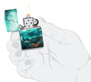 Briquet Zippo 540° vue de face ouvert et allumé en main stylisée  et fait de métal, avec une illustration en couleur qui montre une scène de cimetière brumeuse qui s'étend tout autour du briquet.