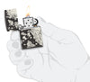 Briquet Zippo 360° vue de face ouvert et allumé en main stylisée  fait de métal, avec une illustration en couleur qui montre une multitude de motifs nautiques avec un voilier ainsi qu'une carte au trésor et des pièces d'or
