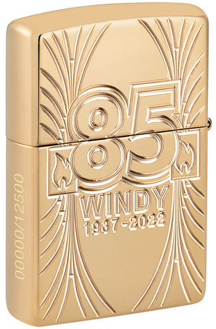 Briquet Zippo ¾ angle vue de l'arrière en couleur dorée et fait de métal, avec une illustration gravée en couleur qui montre Windy, notre modèle publicitaire préféré pour célébrer les 85 ans de Zippo