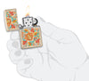 Briquet Zippo couleur sable avec motif floral de style hippie ouvert avec flamme dans une main stylisée