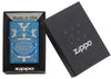 Briquet Zippo bleu vue de face dans une boite cadeau noire ouverte entouré d’un motif en filigrane gravé au laser qui montre le logo de Zippo et de "an american classic".