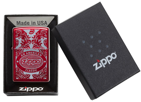 Briquet Zippo rouge vue de face dans une boite cadeau noire ouverte entouré d’un motif en filigrane gravé au laser qui montre le logo de Zippo et de "an american classic".
