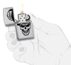 Briquet Zippo chromé tête de mort avec casquette Zippo, ouvert avec flamme dans une main stylisée