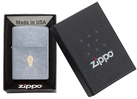 Briquet Zippo chromé avec araignée suspendue à un fil, dans une boîte ouverte