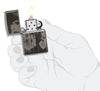 Vue de face briquet Zippo noir haute brillance avec motif de l'artiste Spazuk, ouvert avec flamme dans une main stylisée