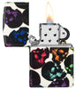 Briquet Zippo 540° vue de face Skulls Design avec des têtes de mort multicolores brillant dans la nuit ouvert et allumé